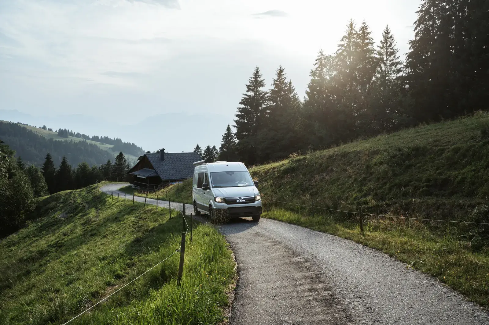 Castello Camper auf einer schmalen Bergstraße, vorbei an einer Holzhütte