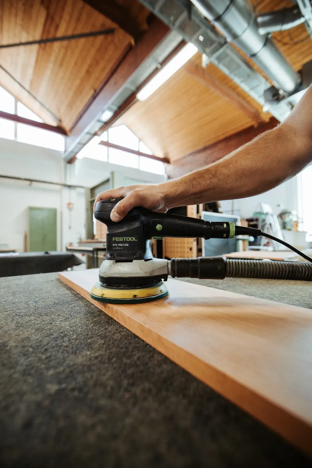 Eine Holzplatte wird in der Werkstatt geschliffen